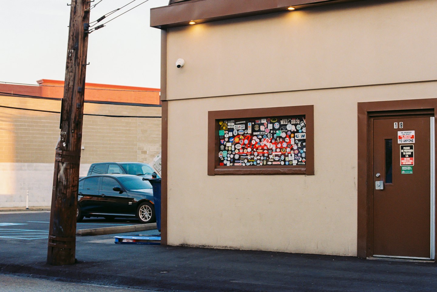 Beige commercial building with a sticker-filled window and warning signs.